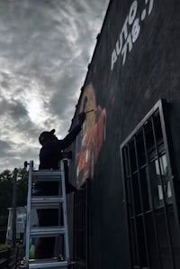a man painting a mural on the side of a building